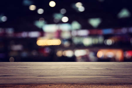 background Image of wooden table in front of abstract blurred restaurant lightsの写真素材