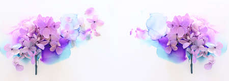 Creative image of pastel violet and pink Hydrangea flowers on artistic ink background. Top view with...