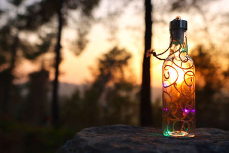 image of mystic bottle with glitter lights in the woods at sunsetの写真素材
