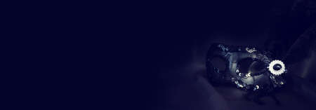 Photo of elegant and delicate black Venetian mask over dark silk backgroundの写真素材
