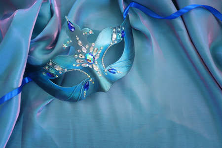 Photo of elegant and delicate Venetian mask over blue silk backgroundの写真素材