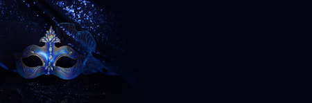 Photo of elegant and delicate Venetian mask over blue dark background