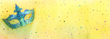 Photo of elegant and delicate Venetian mask over yellow glitter chiffon backgroundの写真素材