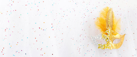 Photo of elegant and delicate Venetian mask over white glitter chiffon backgroundの写真素材