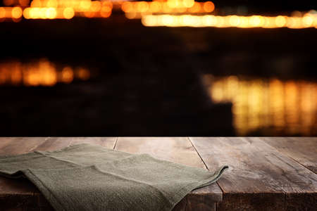 background Image of wooden table in front of abstract blurred restaurant lightsの写真素材