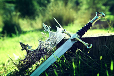 mysterious and magical photo of gold king crown and sword in the England woods. Medieval period...
