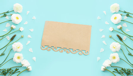 Top view image of white flowers composition and empty note over blue pastel backgroundの写真素材