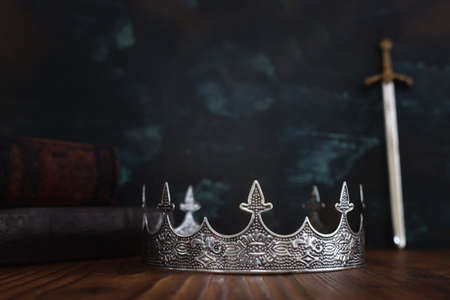 low key image of beautiful queen or king crown, antique book next to sword. fantasy medieval period. Selective focusの写真素材