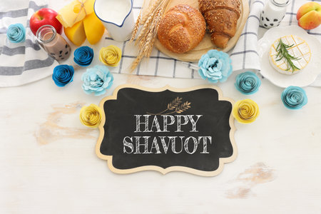 top view photo of dairy products over white wooden background. Symbols of jewish holiday - Shavuot