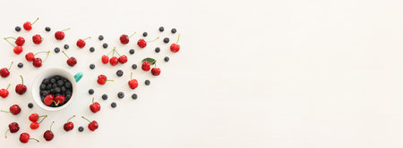 Top view image of colorful assorted mix of berries, blueberry and sweet cherry over wooden white...