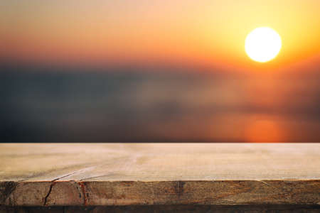 Wooden table and blurred sunset background. Summertime and vacation