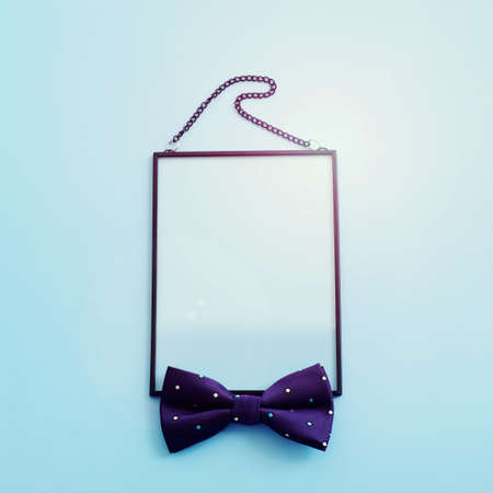 Father's day concept. bow tie and empty photo frame over blue background. top view, flat lay