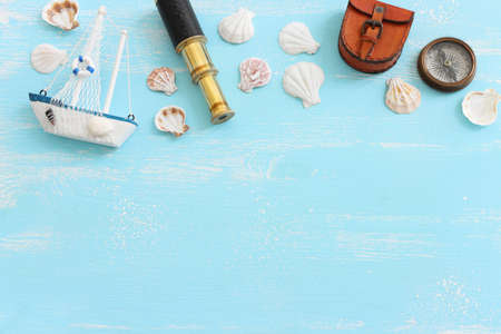 nautical concept with white sail boat, seashells, old retro compass and binoculars over blue wooden backgroundの写真素材