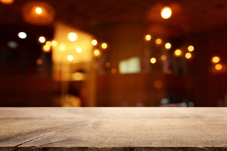 background Image of wooden table in front of abstract blurred restaurant lights