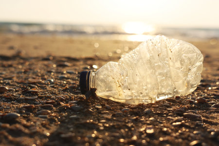 Plastic bottle thrown on the beach . Concept of environmental pollution and damage to nature and...