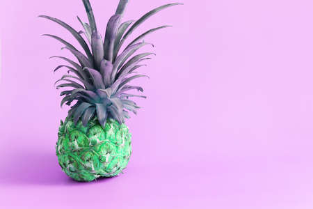 abstract photo of green pineapple over neon purple background. Holidays, beach and tropical themeの写真素材