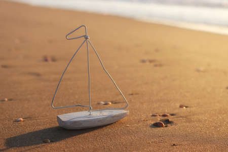 Small wooden boat on beach at summer sunset