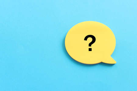 Top view image of sticky note and question mark over textured paper