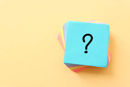 Top view image of sticky note and question mark over textured paper