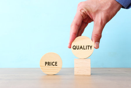 A hand chooses a cube with the word quality, versus priceの写真素材