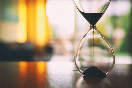 Vintage hourglass clock over tableの写真素材