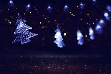 Christmas tree garland lights over dark background with glitter overlay