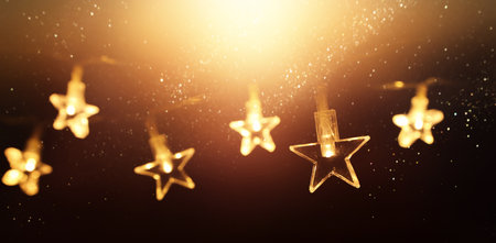 Christmas warm gold garland lights over dark background with glitter overlay
