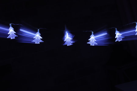 Christmas tree garland lights over dark background with glitter overlayの写真素材