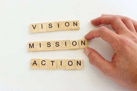 The words vision, action and mission written on wooden cubes over white background