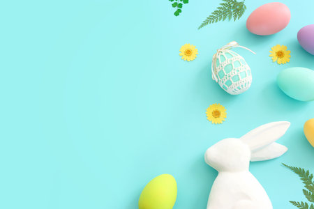 Cute bunny next to easter colorful eggs over blue pastel background