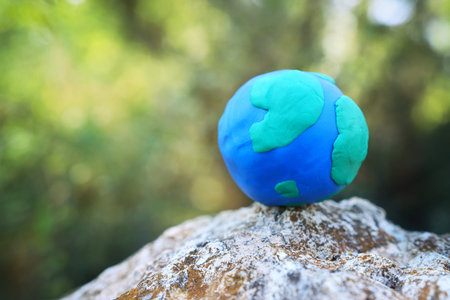 Model of earth on the ground in the forest with bright sun light. Sustainability and ecology conceptの写真素材