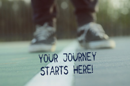 View of shoes on asphalt with the text your journey starts here. Concept of new challenge and moving forwardの写真素材