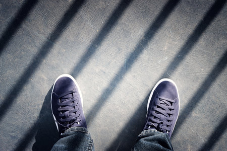 View of sneakers on asphalt road, man moving forward