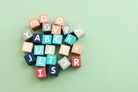 Wooden cubes with English letters on a pastel green background. ABC learning, education and language...
