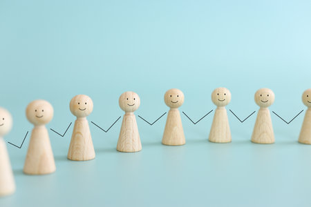 Concept image of wooden figures holding hands. An idea of unity, cooperation and successの写真素材