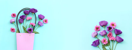Top view image of pink and purple flowers composition over pastel blue background .Flat lay