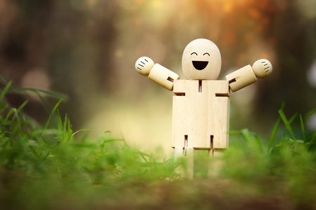 Wooden figure in nature with smiling face. Concept of joy happiness and wellnessの写真素材