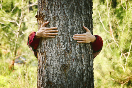 Young woman hugging tree trunk. concept of nature preservation and ecologyの写真素材