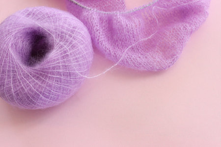 Purple cozy yarn ball of alpaca wool over pink background