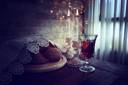 Low key shabbat image. challah bread, shabbat wine and candles on wooden tableの写真素材