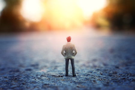 Concept image of lonely figure walking in sunset towards the horizonの写真素材