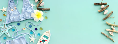 Top view of female swimsuit bikini, starfish, boat and monoi flower over pastel blue background....