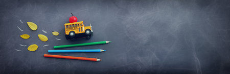 Back to school concept. bus and pencils over classroom blackboard. Top view