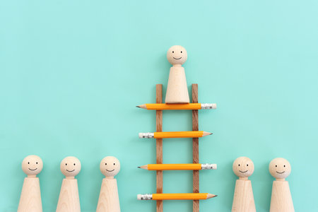 Concept image of a ladder made of pencils and wooden figure on top. Idea of education, success and achieving goalsの写真素材