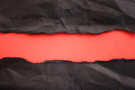 Black torn paper on red backgroundの写真素材