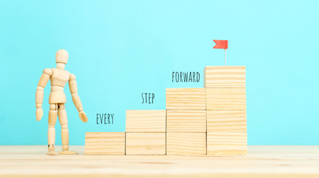 Concept of leadership and forwarding ahead. Wooden figure with red flag on top of stairs
