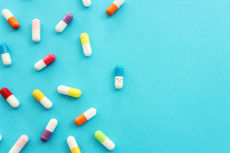 Colorful pills with smiling face on blue background. Idea of finding successful treatment and health