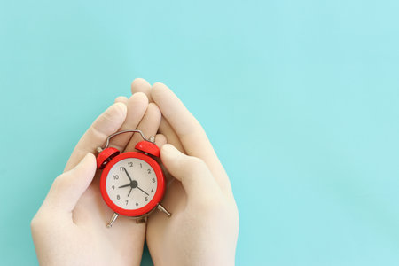 Hand with medical gloves holding red clock. Concept of healthcare and treatment