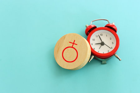 Red vintage clock and wooden circle with female gender symbolの写真素材