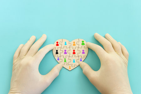 Top view image of doctor or nurse with gloves and puzzle pieces over blue backgroundの写真素材